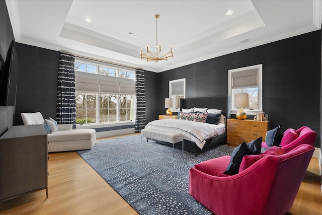 bedroom featuring recessed lighting, wood finished floors, ornamental molding, a tray ceiling, and an inviting chandelier