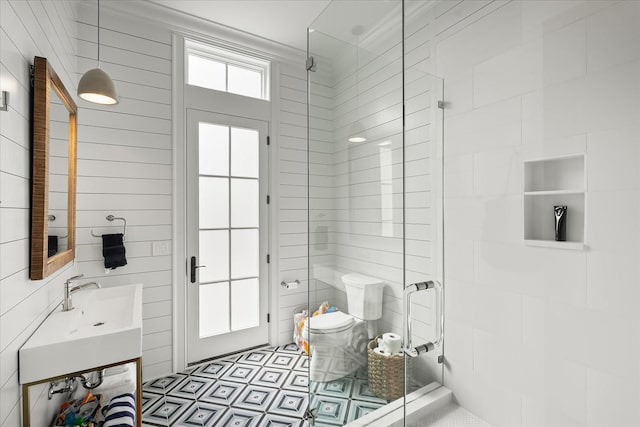 full bathroom featuring a stall shower, wood walls, vanity, and toilet