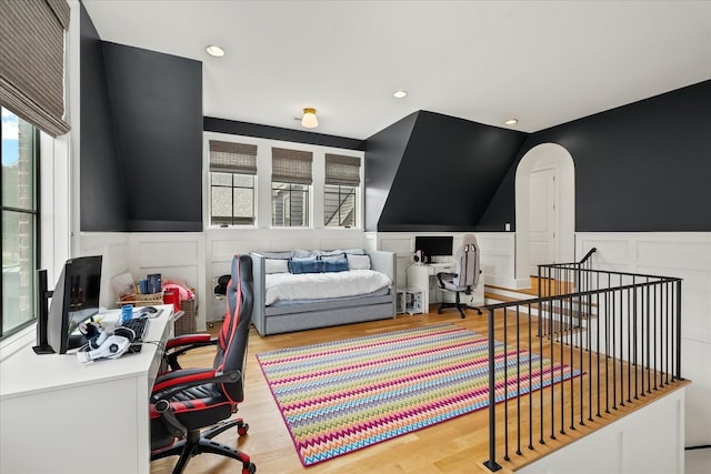 bedroom featuring light wood-type flooring, a wainscoted wall, and multiple windows