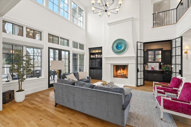 living area with a chandelier, a lit fireplace, and wood finished floors