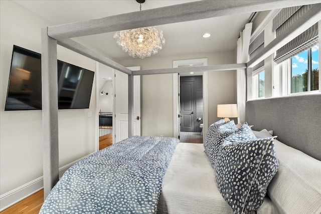 bedroom featuring recessed lighting, wood finished floors, an inviting chandelier, and baseboards