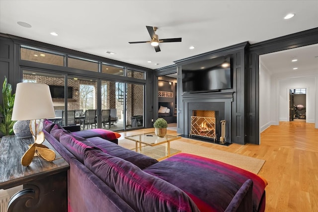 living area featuring crown molding, recessed lighting, visible vents, light wood-style floors, and a large fireplace