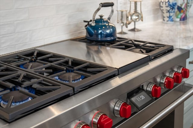 details featuring stainless steel gas stove and backsplash