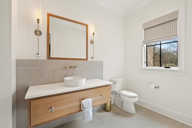 bathroom featuring backsplash, toilet, ornamental molding, vanity, and baseboards