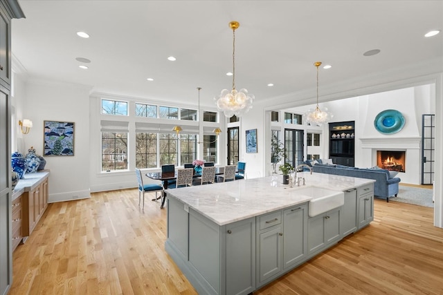 kitchen featuring light wood-style floors, ornamental molding, gray cabinets, and a sink