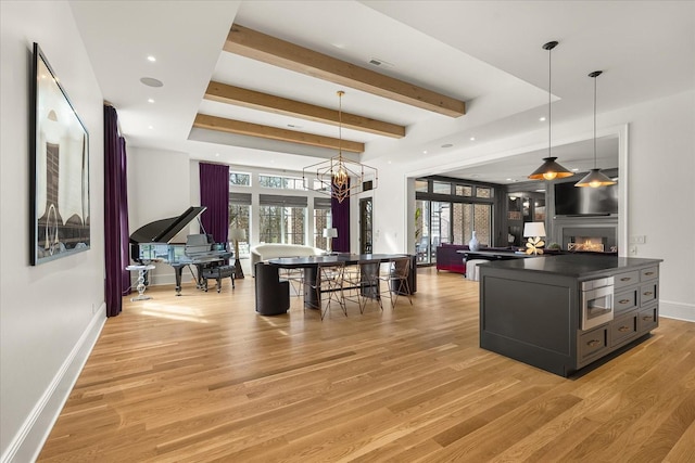 kitchen with open floor plan, a warm lit fireplace, dark countertops, and light wood-style flooring