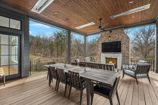 wooden deck featuring an outdoor living space with a fireplace, outdoor dining area, and a ceiling fan