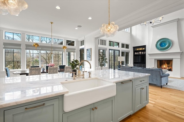 kitchen with a lit fireplace, ornamental molding, open floor plan, and a sink