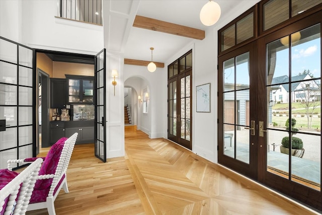 doorway to outside featuring arched walkways, french doors, beamed ceiling, baseboards, and parquet flooring