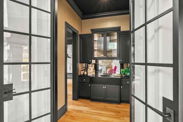 bar featuring light wood finished floors and ornamental molding