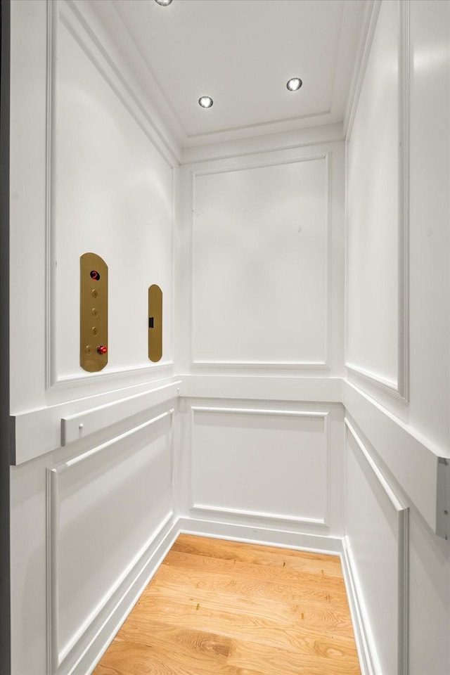 details featuring elevator, wood finished floors, crown molding, a decorative wall, and recessed lighting