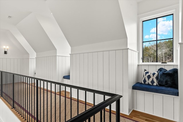 hall with vaulted ceiling, wainscoting, and wood finished floors