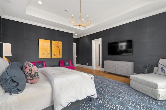 bedroom featuring a tray ceiling, visible vents, crown molding, and wood finished floors