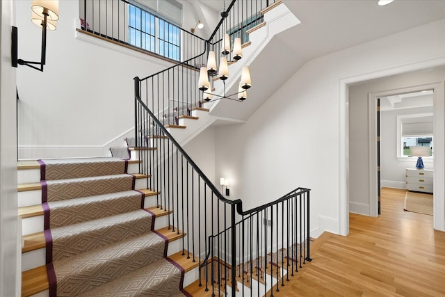 stairway featuring a high ceiling, baseboards, and wood finished floors