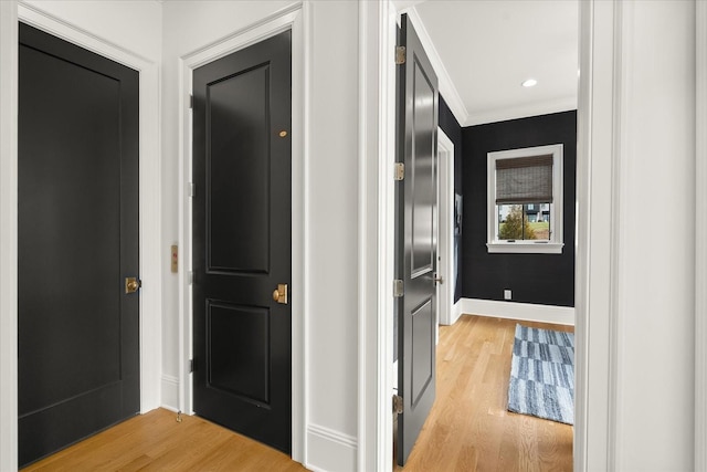 corridor featuring baseboards, light wood finished floors, recessed lighting, and crown molding