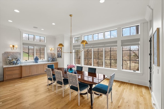 dining area featuring light wood-type flooring and crown molding