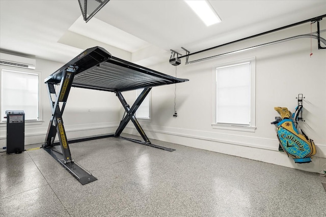 workout room featuring a garage, a wealth of natural light, a wall mounted air conditioner, and baseboards