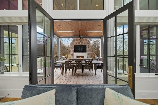 sunroom / solarium with wooden ceiling, ceiling fan, a brick fireplace, and a wealth of natural light