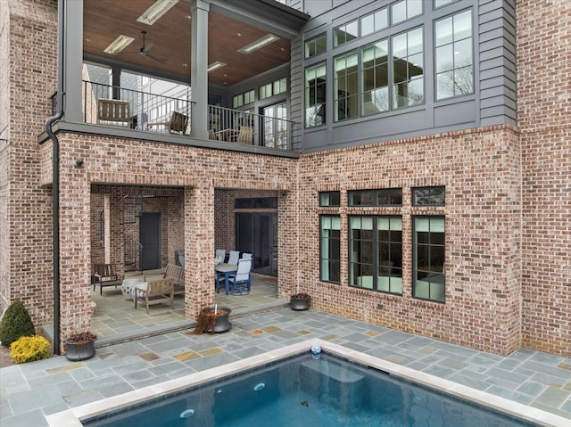 rear view of house with a patio area, brick siding, and a balcony