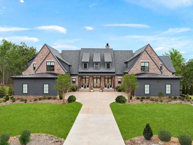 view of front of house featuring driveway, a standing seam roof, a front lawn, and brick siding