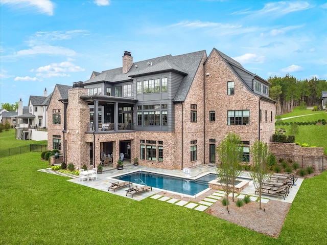 rear view of house featuring a lawn, a patio, a balcony, fence, and brick siding