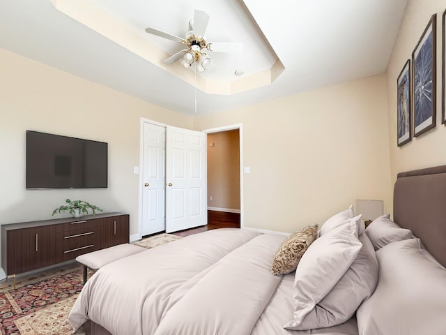 bedroom featuring ceiling fan, a raised ceiling, and baseboards