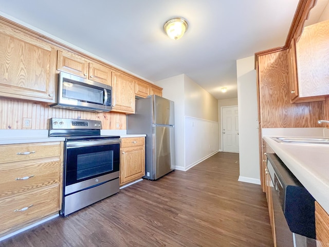 kitchen with stainless steel appliances, dark wood-style flooring, light countertops, and a sink