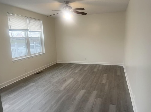 spare room featuring a ceiling fan, dark wood-style flooring, visible vents, and baseboards