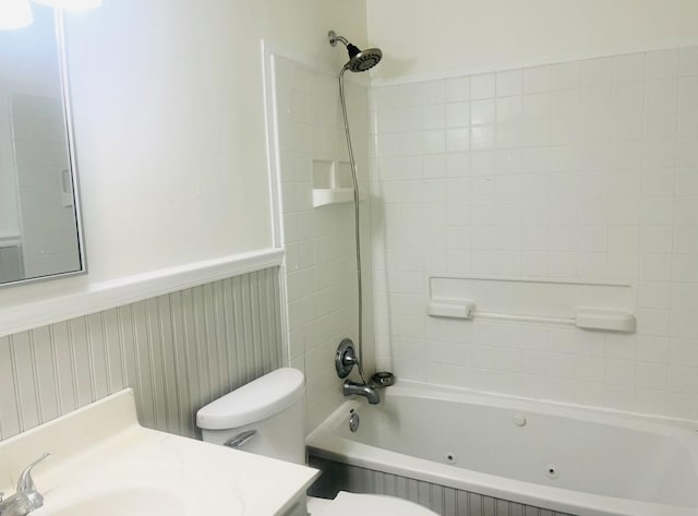 full bath with toilet, wainscoting, a combined bath / shower with jetted tub, and vanity