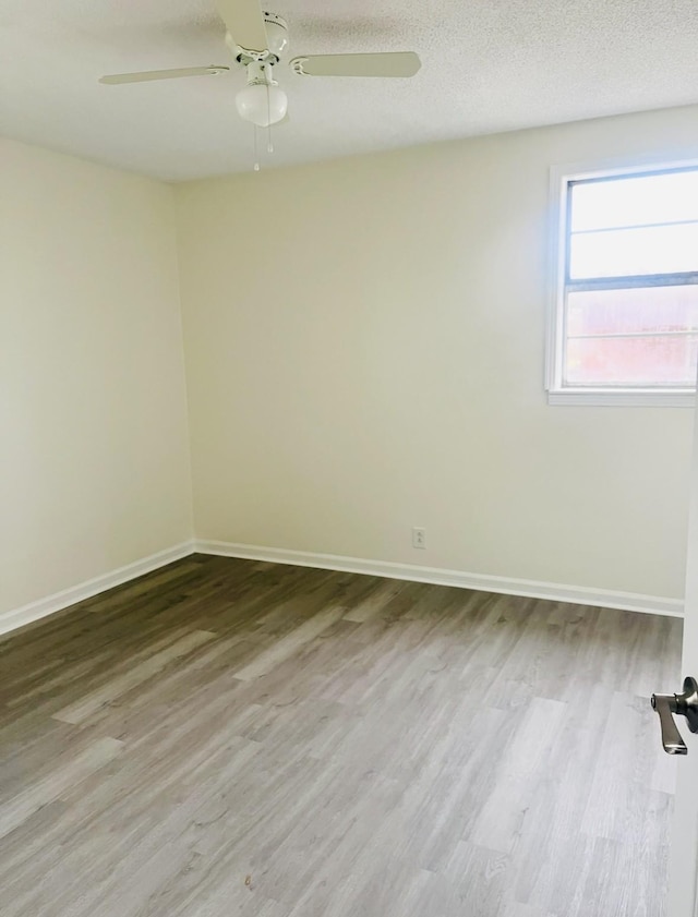 spare room featuring a textured ceiling, baseboards, and wood finished floors