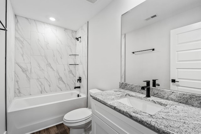 bathroom featuring toilet, wood finished floors, vanity, visible vents, and tub / shower combination