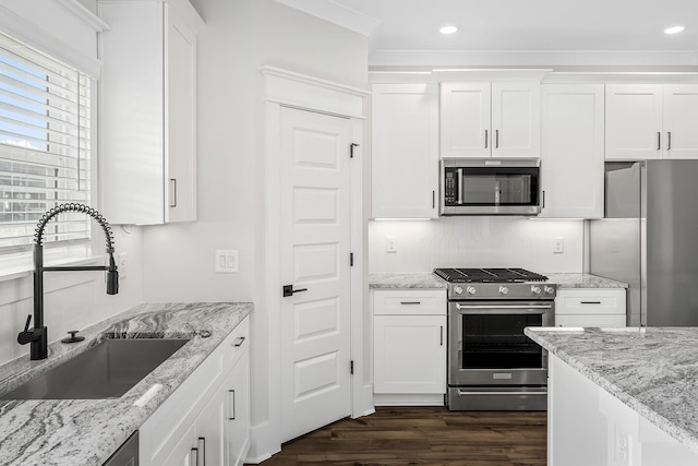 kitchen with a sink, white cabinetry, appliances with stainless steel finishes, backsplash, and dark wood-style floors