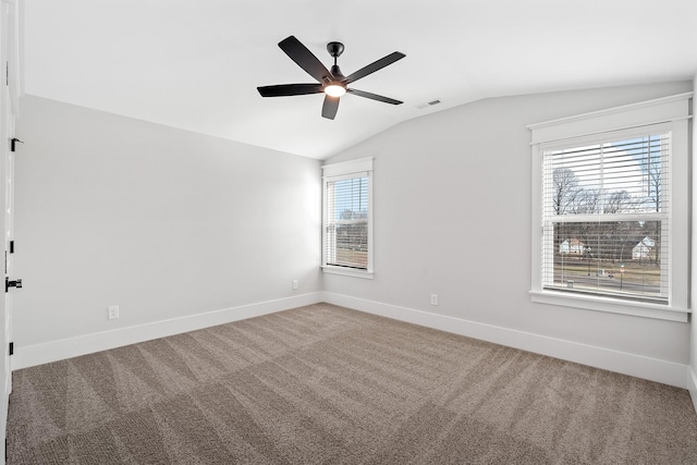 carpeted spare room featuring a ceiling fan, visible vents, vaulted ceiling, and baseboards