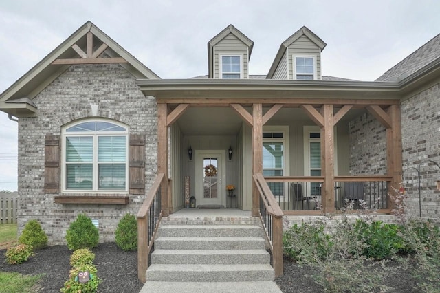 entrance to property featuring covered porch and brick siding