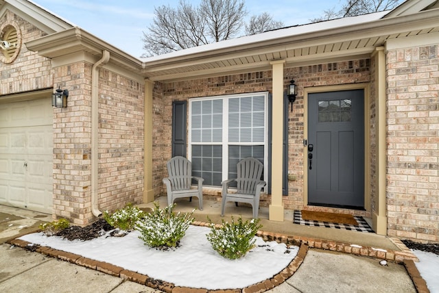 entrance to property with a garage, a porch, and brick siding