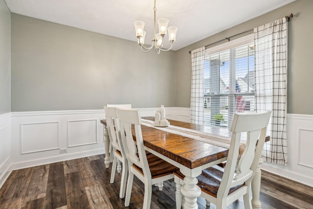 dining space with an inviting chandelier, dark wood-style flooring, and a wainscoted wall