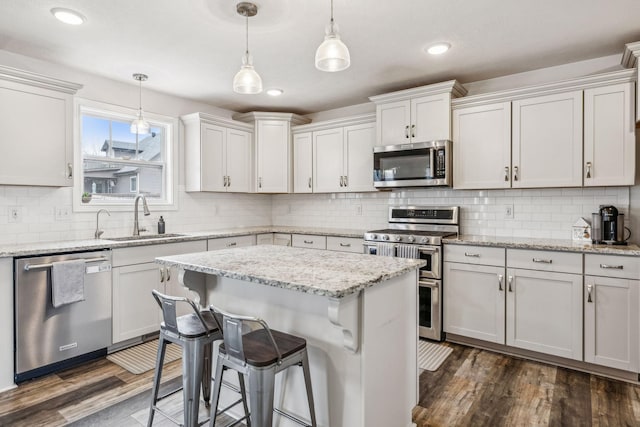 kitchen with a breakfast bar, dark wood-style flooring, decorative light fixtures, stainless steel appliances, and a sink