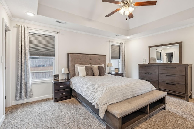 bedroom featuring crown molding, a tray ceiling, visible vents, and light colored carpet