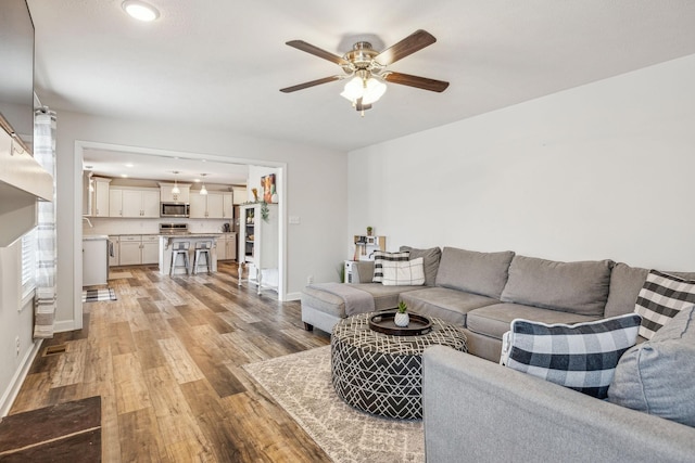 living area featuring light wood-style floors, recessed lighting, ceiling fan, and baseboards