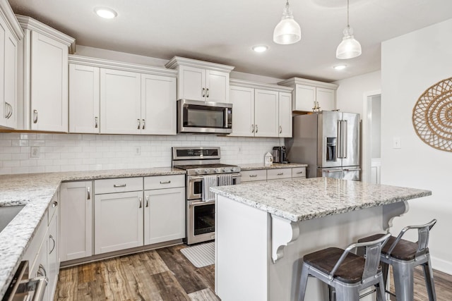 kitchen featuring decorative backsplash, stainless steel appliances, dark wood-style flooring, and a kitchen breakfast bar