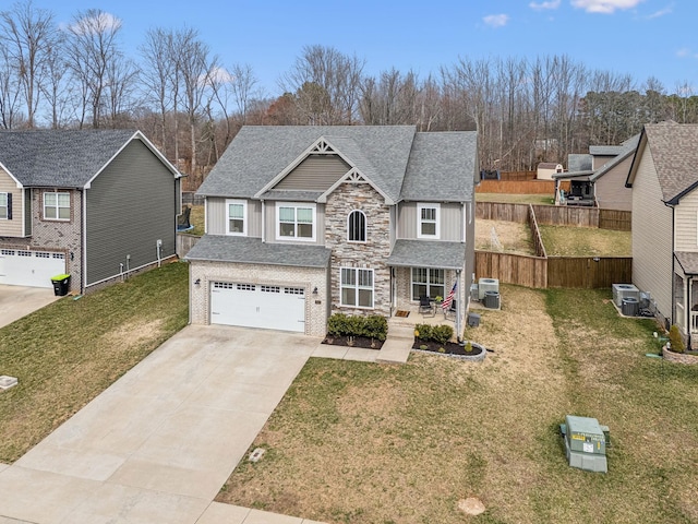 traditional-style house with a shingled roof, concrete driveway, an attached garage, fence, and a front lawn