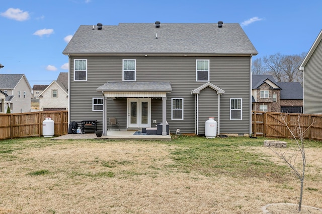 rear view of house with a shingled roof, a lawn, a patio, a fenced backyard, and french doors