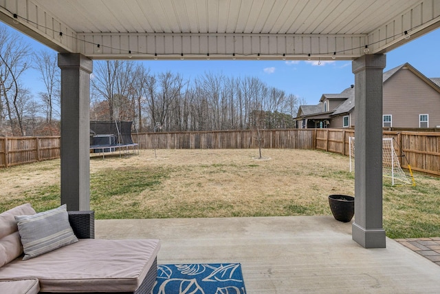 view of yard featuring a trampoline, a fenced backyard, and a patio