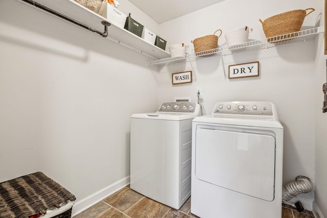 washroom with washing machine and dryer, laundry area, stone finish floor, and baseboards