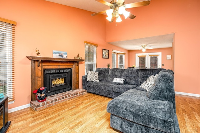 living room with lofted ceiling, ceiling fan, a fireplace, wood finished floors, and baseboards