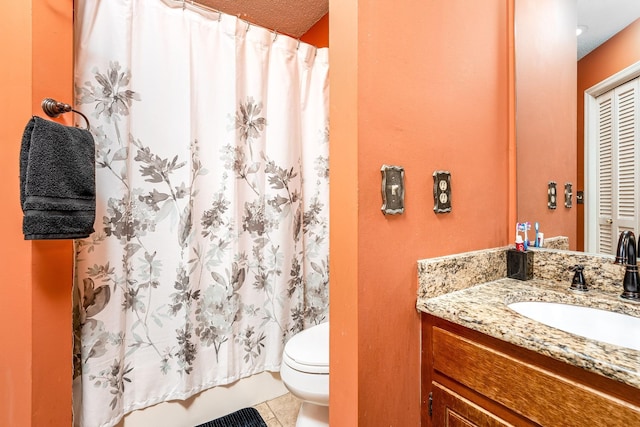 bathroom with a textured ceiling, vanity, toilet, and tile patterned floors