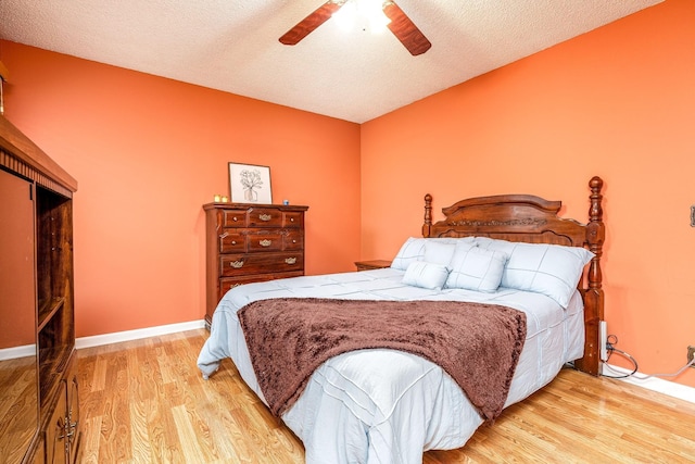 bedroom featuring a textured ceiling, light wood finished floors, a ceiling fan, and baseboards