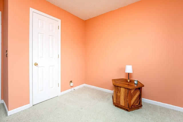 carpeted spare room featuring a textured ceiling and baseboards