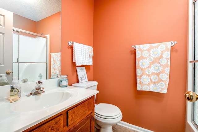 full bathroom featuring toilet, a shower with door, a textured ceiling, and vanity