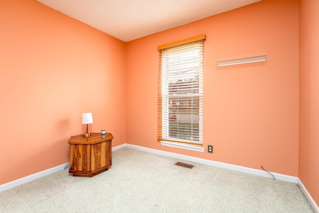 carpeted empty room with baseboards, visible vents, and a textured ceiling